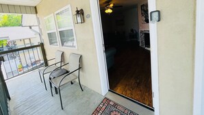 A covered porch with a patio table and chairs, a wooden deck, and a door leading to an interior living area with a fireplace. - Downtown of Pigeon Forge. Cozy 1 bed 1 bath condo <br>208 (Pigeon Forge)