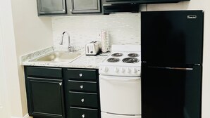 A compact kitchen with dark cabinets, a white stove, a black refrigerator, and a tiled backsplash. - Downtown of Pigeon Forge. Cozy 1 bed 1 bath condo <br>208 (Pigeon Forge)