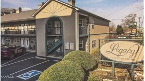 A multi-story building with a central staircase, a parking lot, and a sign for Legacy Condominiums. - Downtown of Pigeon Forge. Cozy 1 bed 1 bath condo <br>208 (Pigeon Forge)