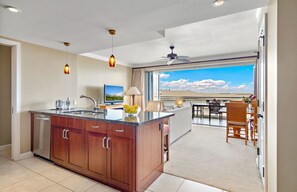 Una cocina moderna con una isla central, un comedor con vistas y un ventilador de techo.