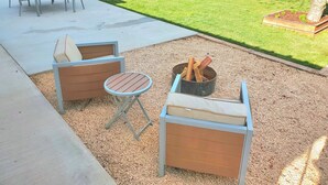 A patio area with a table and two wooden chairs, a small round table, and a fire pit. - Comfortable, Laid-back Cottage. Private Yard. Near Zion. 2 Bedroom, Full Kitchen (Hurricane)