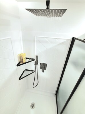 Eine Dusche mit Regendusche, Handbrause und Handbrause mit schwarzem Schlauch.