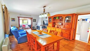 Un salon chaleureux avec un canapé, une table à manger et des chaises, ainsi qu’un coin cuisine doté de meubles en bois et d’un réfrigérateur.