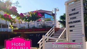 A hotel entrance with a sign for a restaurant and pizzeria, a staircase, and a gate with a bar and hotel parking sign. - La Luna Resort Ksamil (Ksamil)