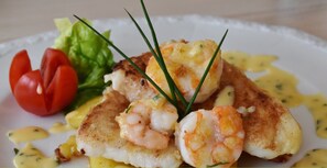 Un plato de comida con camarones y una guarnición verde, con la etiqueta 'Hotel Tirana Karkaleca'.