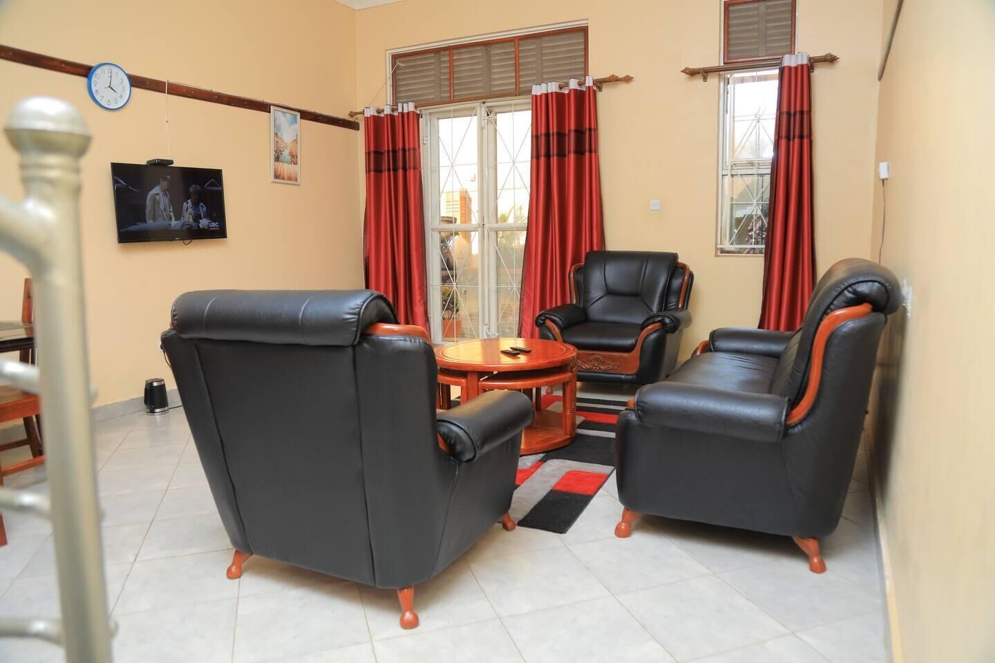 A living room with two black leather sofas, a wooden coffee table, and a television on the wall.