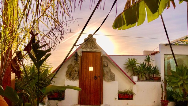 A courtyard with a stone statue, a wooden door, and potted plants. - Studio Sleeps 2 with Free Parking (Mexilhoeira Grande)