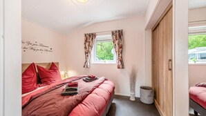 Une chambre à coucher avec un lit, une fenêtre avec des rideaux, un élément de décoration murale et une armoire en bois.