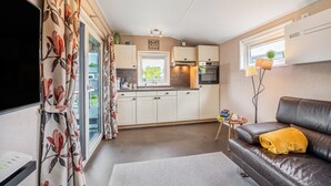 Un espace de vie compact comprenant un coin cuisine, un canapé avec une couverture et un téléviseur à écran plat.