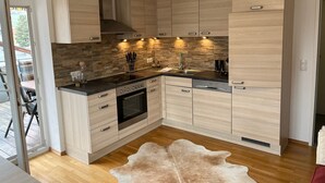 Une cuisine moderne avec des meubles de couleur bois clair, un plan de travail noir et un four encastré.