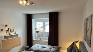 Une chambre avec deux lits, une fenêtre avec des rideaux, une table de chevet avec une lampe et des œuvres d’art accrochées au mur.