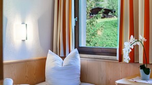 Une pièce avec une fenêtre, un oreiller, une plante et un luminaire fixé au mur.