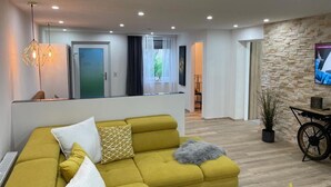 Una sala de estar moderna con un sofá, una televisión y una pared de piedra.