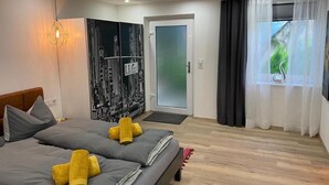 Una habitación de hotel moderna con una cama, un cuadro, una puerta y una ventana.