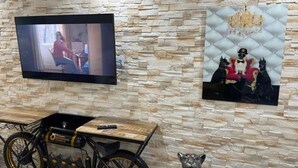 Una habitación con pared de piedra, televisor montado, bicicleta y una estatua.