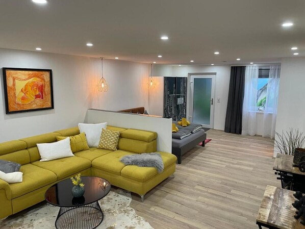 A modern living room with a sectional sofa, a coffee table, and a dining area with a rustic table.