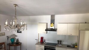 Une cuisine compacte équipée d’un four encastré, d’une cuisinière à gaz et d’un réfrigérateur en acier inoxydable.