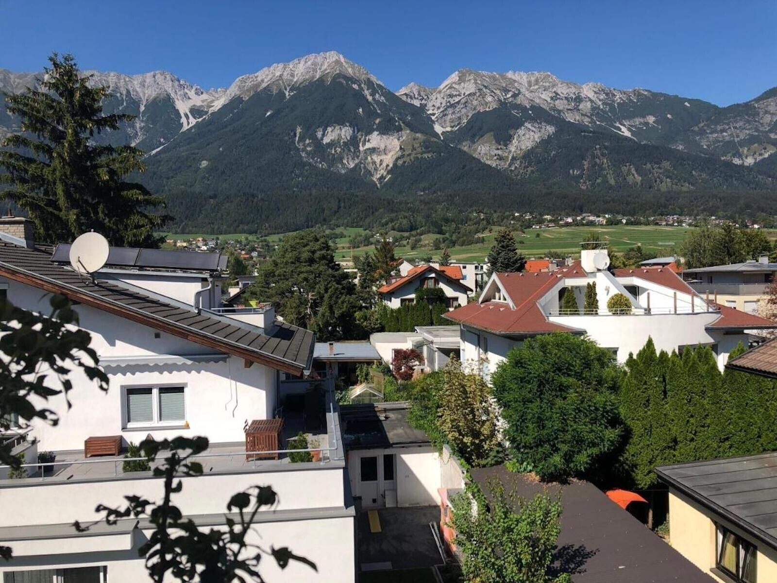 A residential area with modern houses, satellite dishes, and a mountainous backdrop.