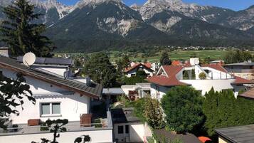 A residential area with modern houses, satellite dishes, and a mountainous backdrop.