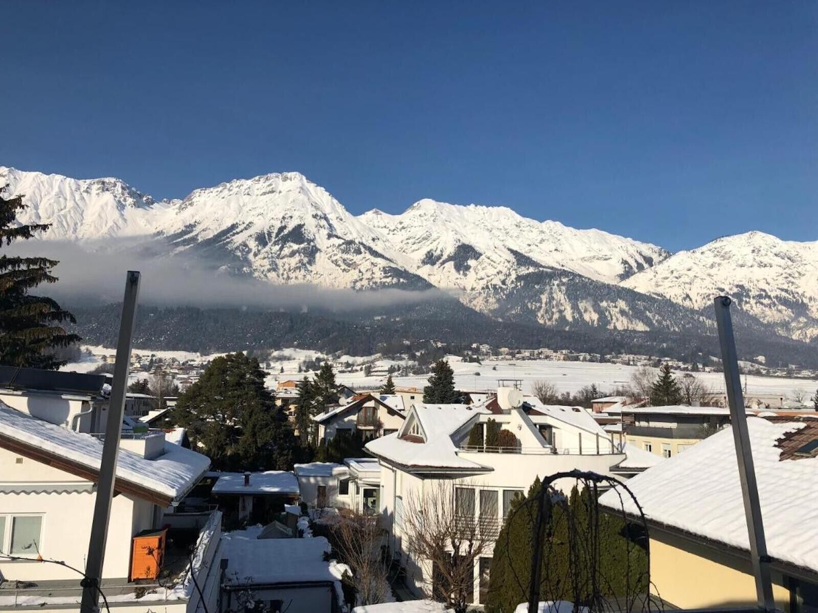 Zona residencial con casas cubiertas de nieve y una cadena montañosa al fondo.