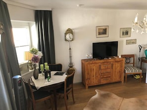 Un salon comprenant une table à manger, des chaises, un téléviseur, un meuble en bois et un canapé.