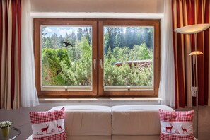 Una habitación con un ventanal grande, un sofá con cojines a cuadros y una lámpara.