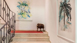 Una escalera con un tapete rojo, barandilla de metal y una figurita de animal en los peldaños.
