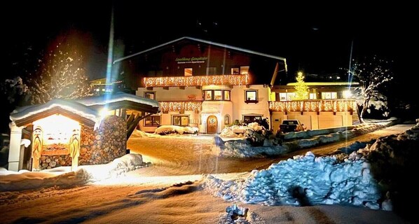 A hotel with a snow-covered entrance, a lit-up facade, and a Christmas tree.
