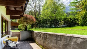 A patio with stone flooring, a yellow table, and a chair. - Apartment W3 Haus Ganghofer with Mountian View, Shared Terrace & Wi-Fi (Leutasch)
