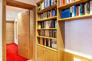Une bibliothèque en bois remplie de livres, un tableau blanc et un sol recouvert d’une moquette rouge.