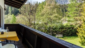 A balcony with a table and chairs, overlooking a forested area with a mountain in the background. - Apartment W4 Haus Ganghofer with Mountain View, Balcony & Wi-Fi (Leutasch)