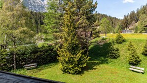 A mountainous landscape with a house, a grassy area, and a bench. - Apartment W4 Haus Ganghofer with Mountain View, Balcony & Wi-Fi (Leutasch)