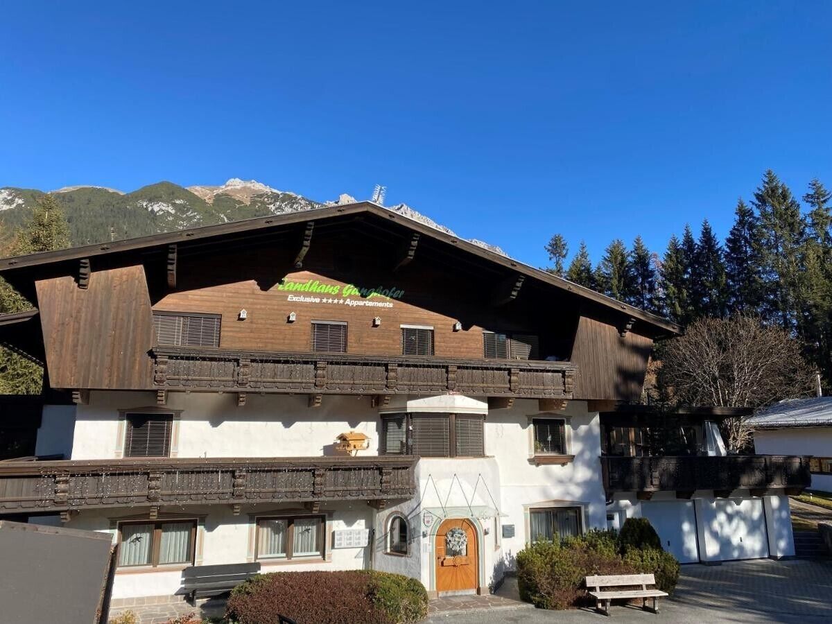 Een traditioneel gebouw in chaletstijl, met een schuin dak, houten balkons en een centrale ingang met een deur.