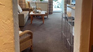 Un salon comprenant un canapé, une table basse et un coin repas avec une chaise en métal.
