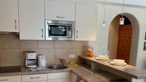 Une cuisine avec des meubles blancs, un four à micro-ondes, une machine à café et un évier.