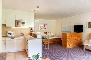 A compact living space with a kitchenette, a bed, a television, and a seating area.