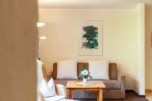 A living room with a sofa, a small table with a vase, and a floor lamp.