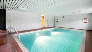 An indoor swimming pool with a tiled floor, a metal handrail, and a white brick wall. - Holiday Apartment 'Haus Lazy Dolphin No. 10' with Sea View and Wi-Fi (Rantum)