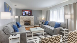 Ein Wohnzimmer mit zwei grauen Sofas, einem weißen Couchtisch und einem Kamin.