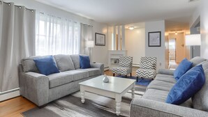 Ein modernes Wohnzimmer mit zwei grauen Sofas, einem weißen Couchtisch und gemusterten Sesseln.