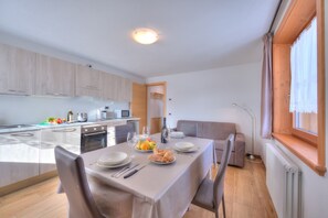 Eine moderne Küche mit Essbereich, Holzausstattung und einem Fenster mit Vorhängen.