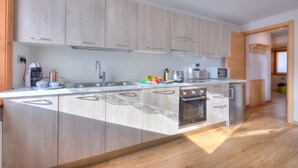 Eine moderne Küche mit hellen Holzschränken, Edelstahlgeräten und einem eingebauten Backofen.