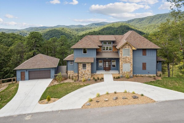 A two-story house with a stone facade, a garage, and a driveway leading to a front entrance.