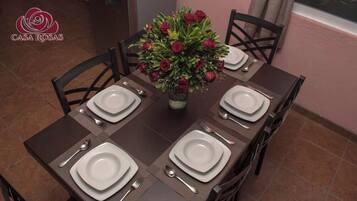 A beautifully set dining table for four, complete with a vase of roses and fine china.