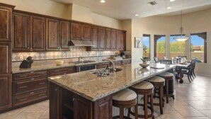 Una cocina amplia con armarios de madera oscura, encimera de granito y una isla grande con taburetes de bar.