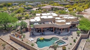 Un gran resort moderno con una piscina central y varias zonas de estar al aire libre.