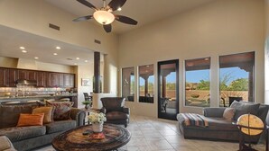 Amplia sala de estar con chimenea, asientos cómodos y ventanas grandes que ofrecen vistas al exterior.