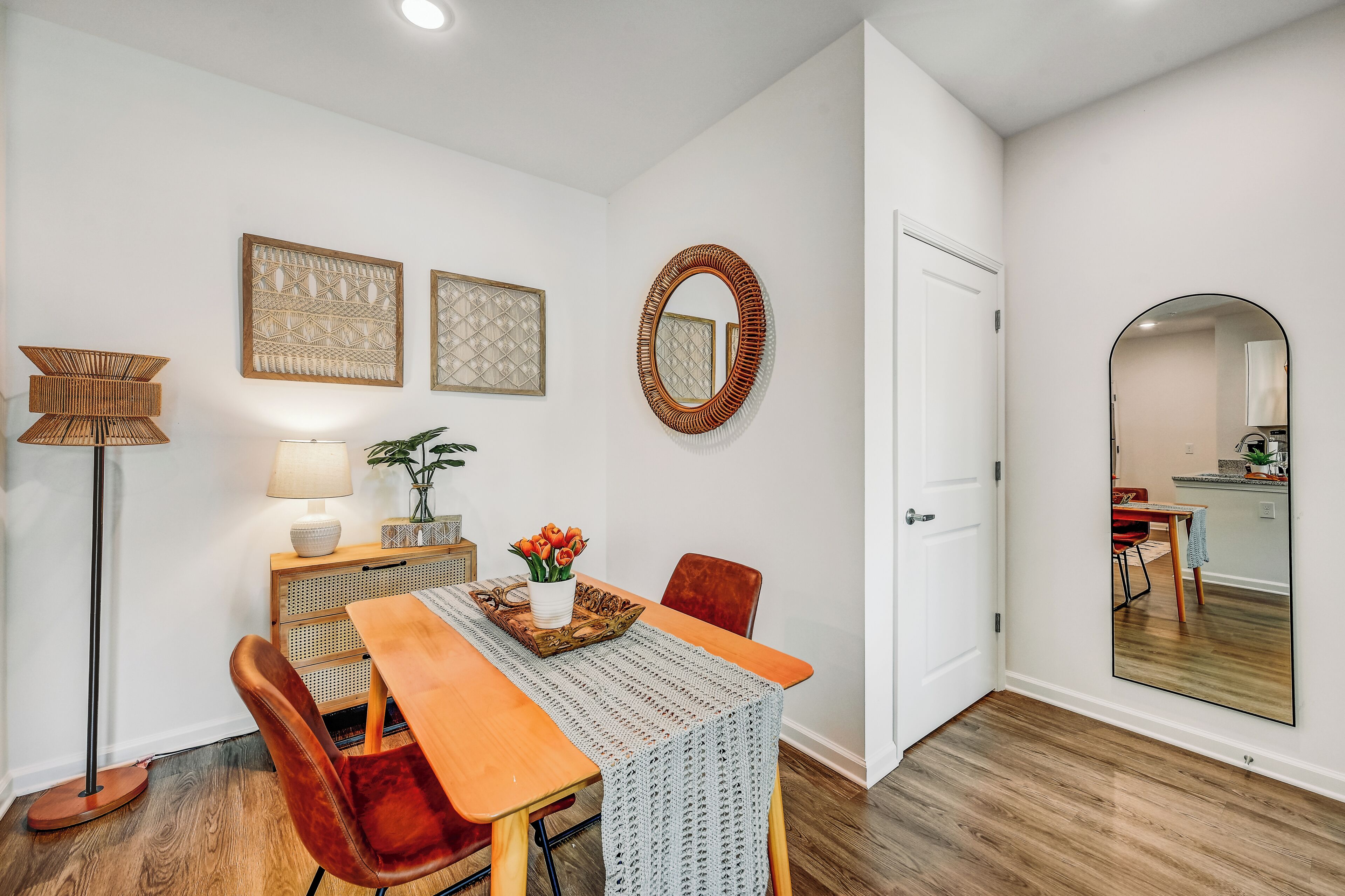 Un comedor con mesa de madera, sillas rojas, una lámpara de pie y decoración en la pared.