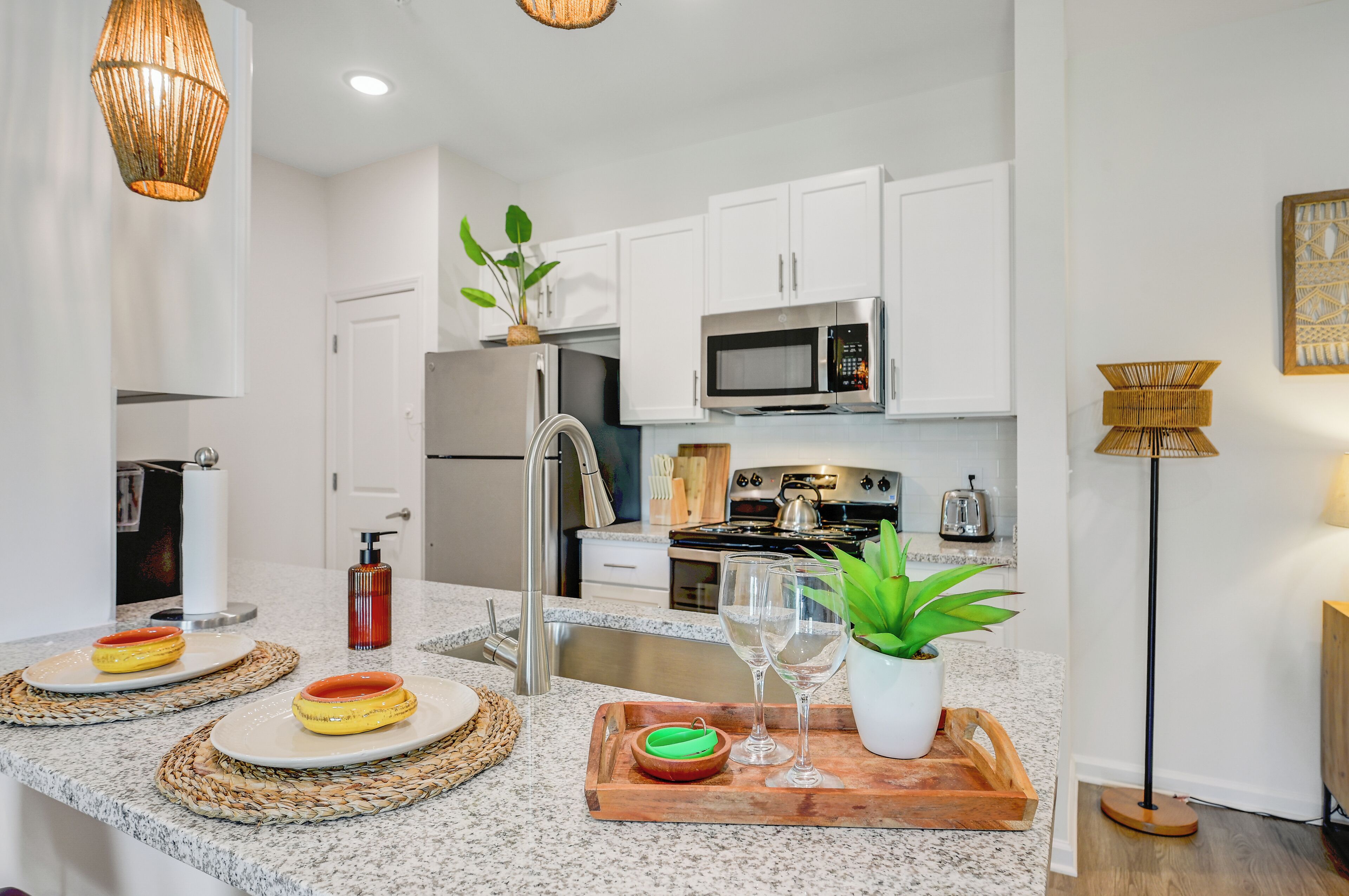 A modern kitchen with white cabinets, stainless steel appliances, and a granite countertop.