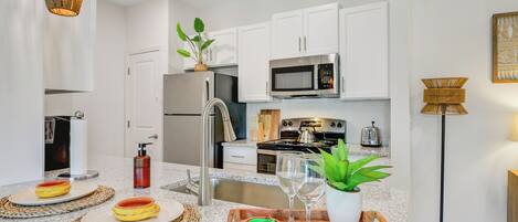 A modern kitchen with white cabinets, stainless steel appliances, and a granite countertop.